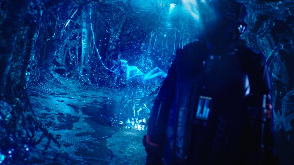 The Image shows a shadowy figure moving into room that it lit with blue